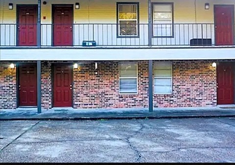 a building with three red doors and a sidewalk