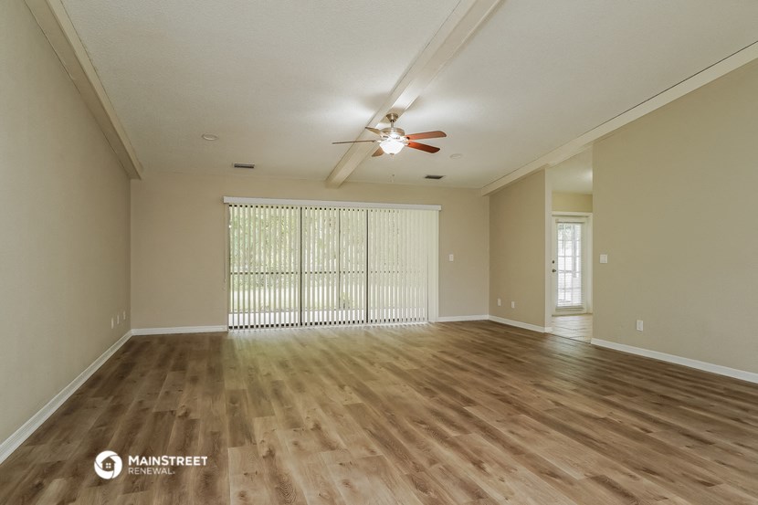 the spacious living room with wood flooring and a ceiling fan