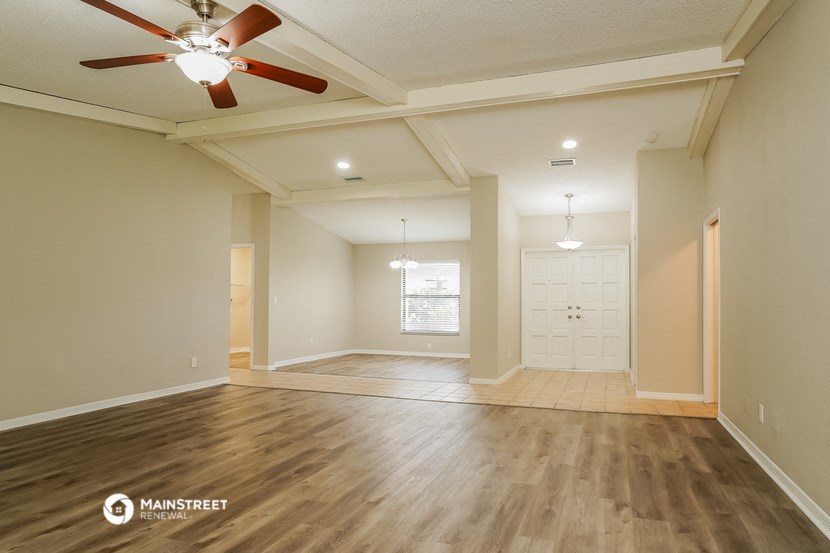 the spacious living room with ceiling fan and wood flooring