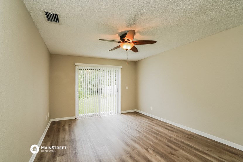 an empty living room with a ceiling fan and a window