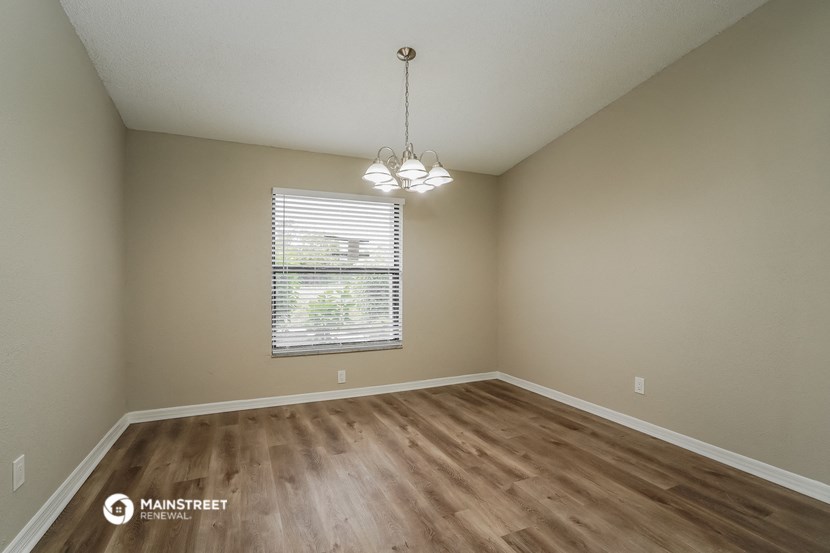 the spacious living room with hardwood flooring and a window