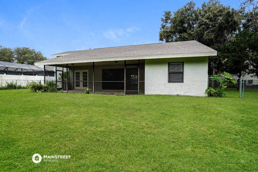 a small white house with a lawn and a fence