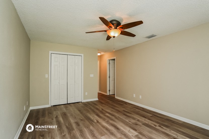 the spacious living room with hardwood flooring and a ceiling fan