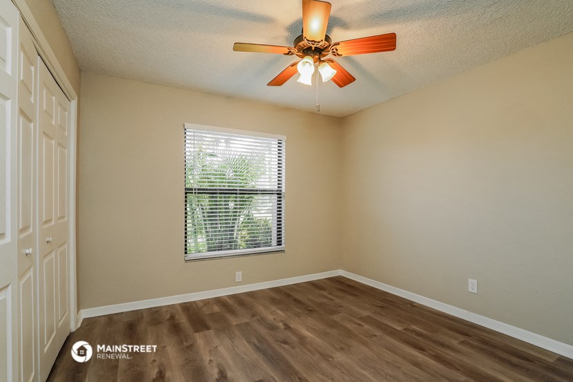 an empty living room with a ceiling fan and a window