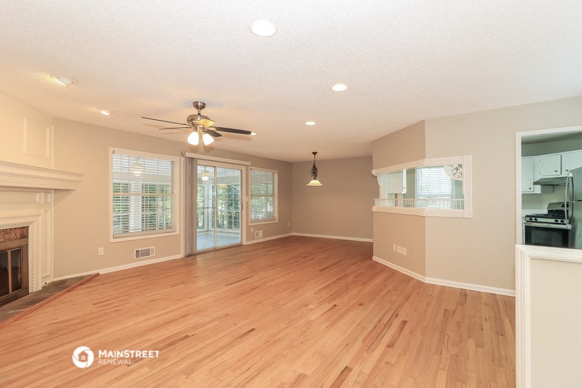 an empty living room with a fireplace and a ceiling fan