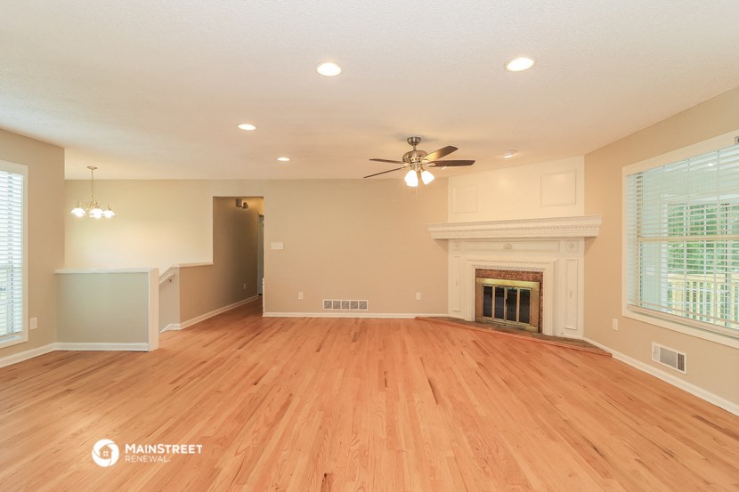 an empty living room with a fireplace and a ceiling fan