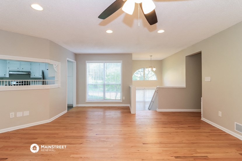 an empty living room with wood floors and a ceiling fan