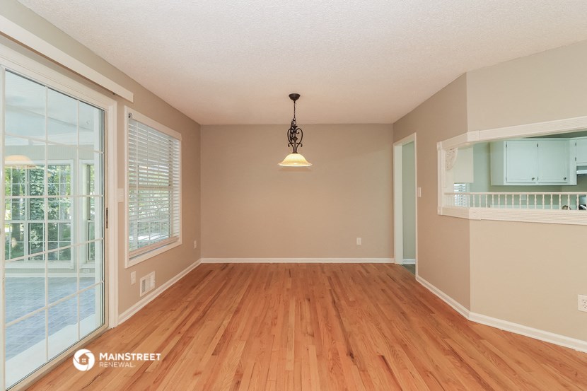 an empty living room with a hard wood floor and a window