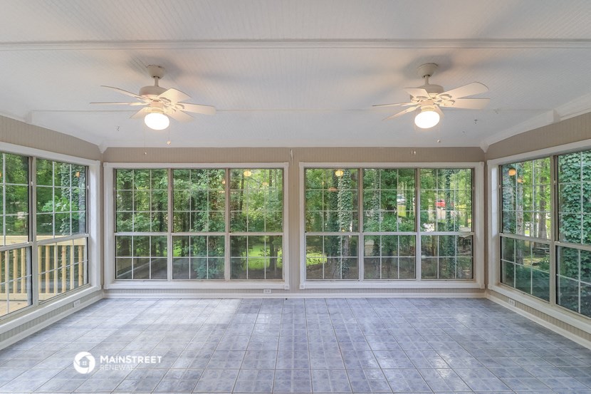 a conservatory with windows and a dance floor and two ceiling fans