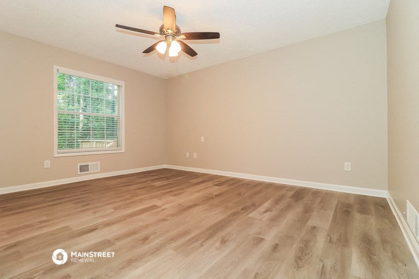 the spacious living room with hardwood floors and a ceiling fan