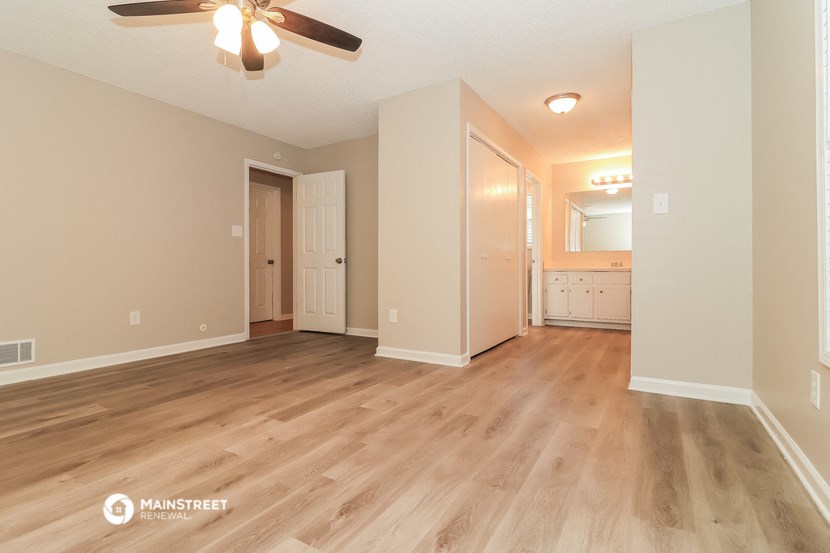 the spacious living room and dining room with hardwood floors and a ceiling fan