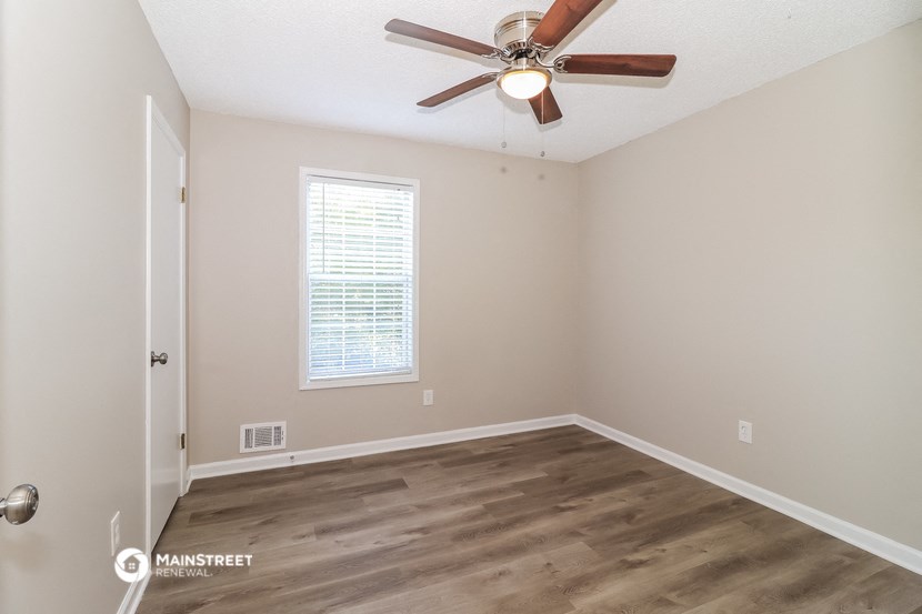 an empty room with a ceiling fan and a window