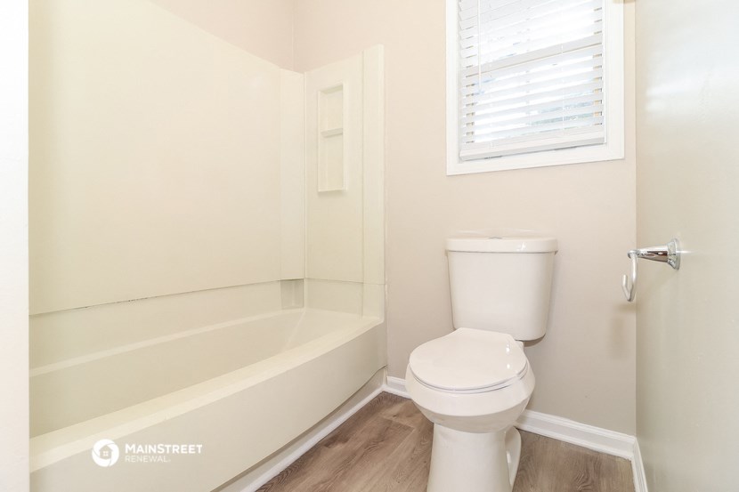 a bathroom with a toilet and a tub and a window