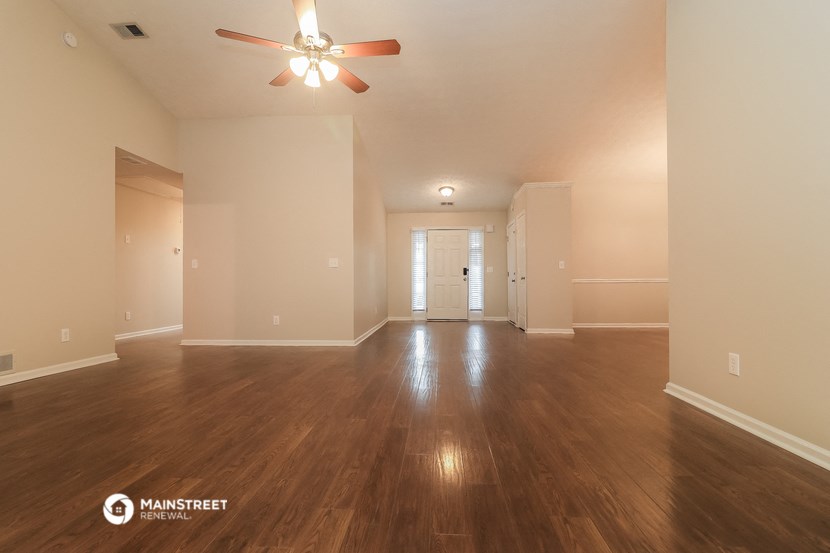 the spacious living room with hardwood flooring and ceiling fan