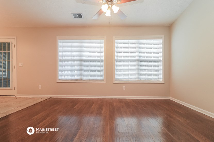 the spacious living room with hardwood floors and a ceiling fan