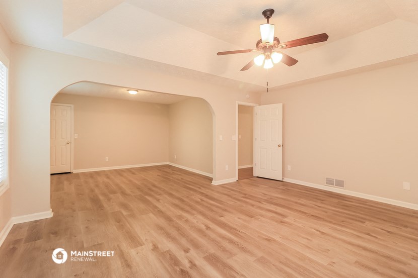 the spacious living room with hardwood floors and a ceiling fan