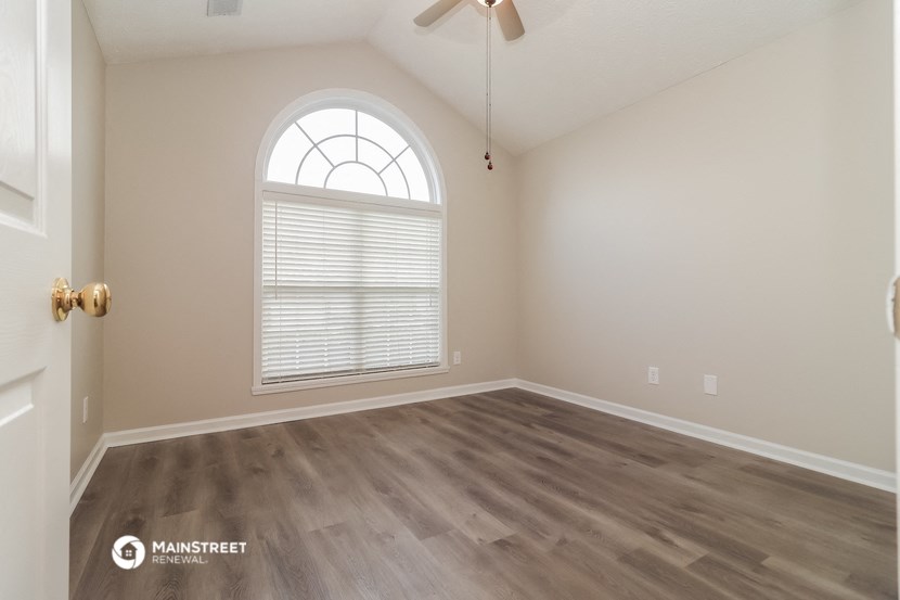 the spacious living room with hardwood flooring and an arched window