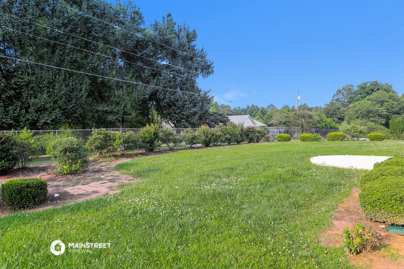a view of the backyard of a house with a field of grass and trees