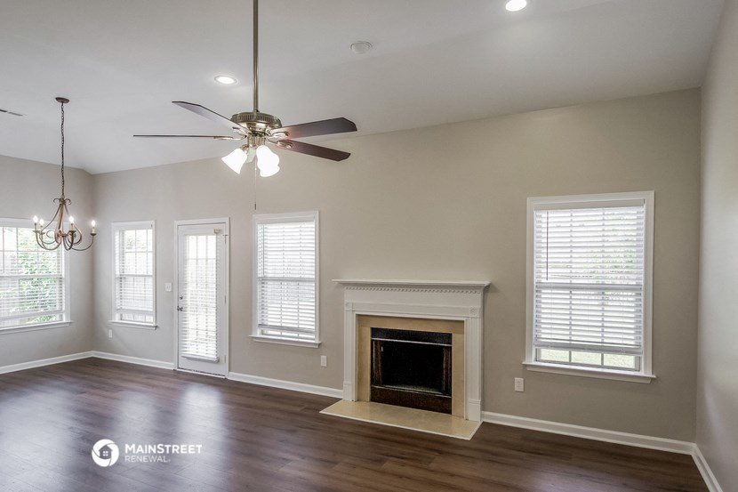 the living room with a fireplace and a ceiling fan