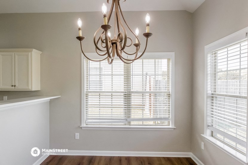 an empty dining room with a large window and a chandelier