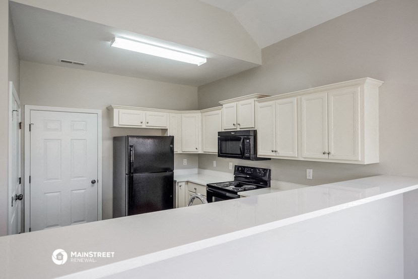 a kitchen with white cabinets and black appliances