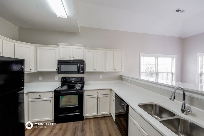 the kitchen of a home with white cabinets and black appliances
