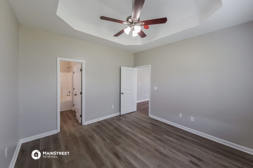 a living room with a ceiling fan and a door to a bathroom