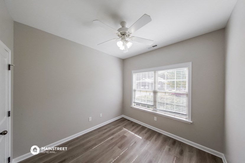 the spacious living room with a ceiling fan and a large window