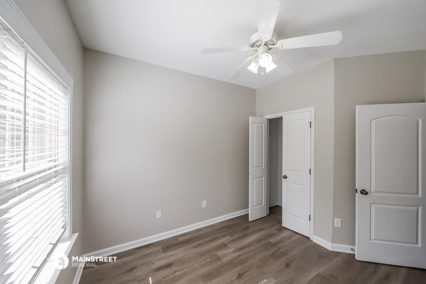 a bedroom with a ceiling fan and a door to a closet