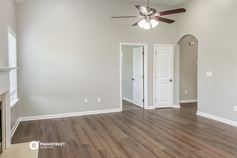 an empty living room with wood floors and a ceiling fan