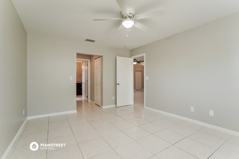 the spacious living room with ceiling fan and tile flooring