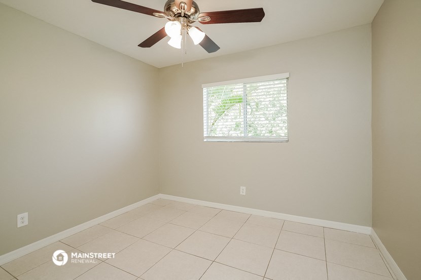 an empty living room with a ceiling fan and a window