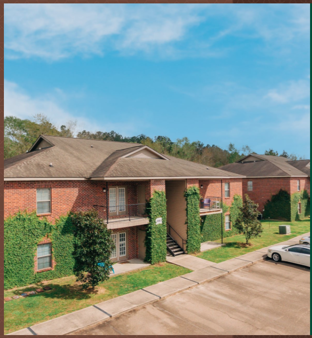 the front of a brick house with green ivy and a sidewalk