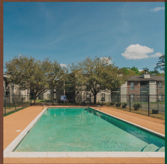 a swimming pool with a fence and apartments in the background