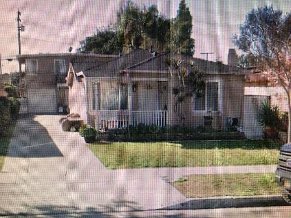 A house with a driveway and a tree in front.