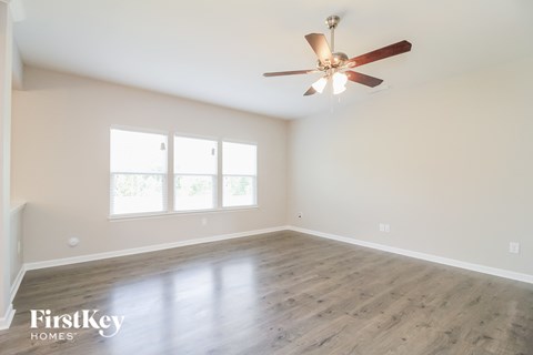 A spacious room with a ceiling fan and wooden flooring.