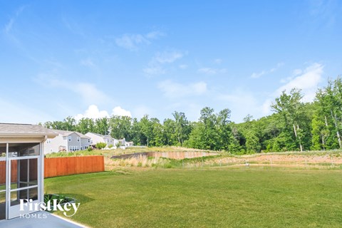 A grassy field with a fence and trees in the background.