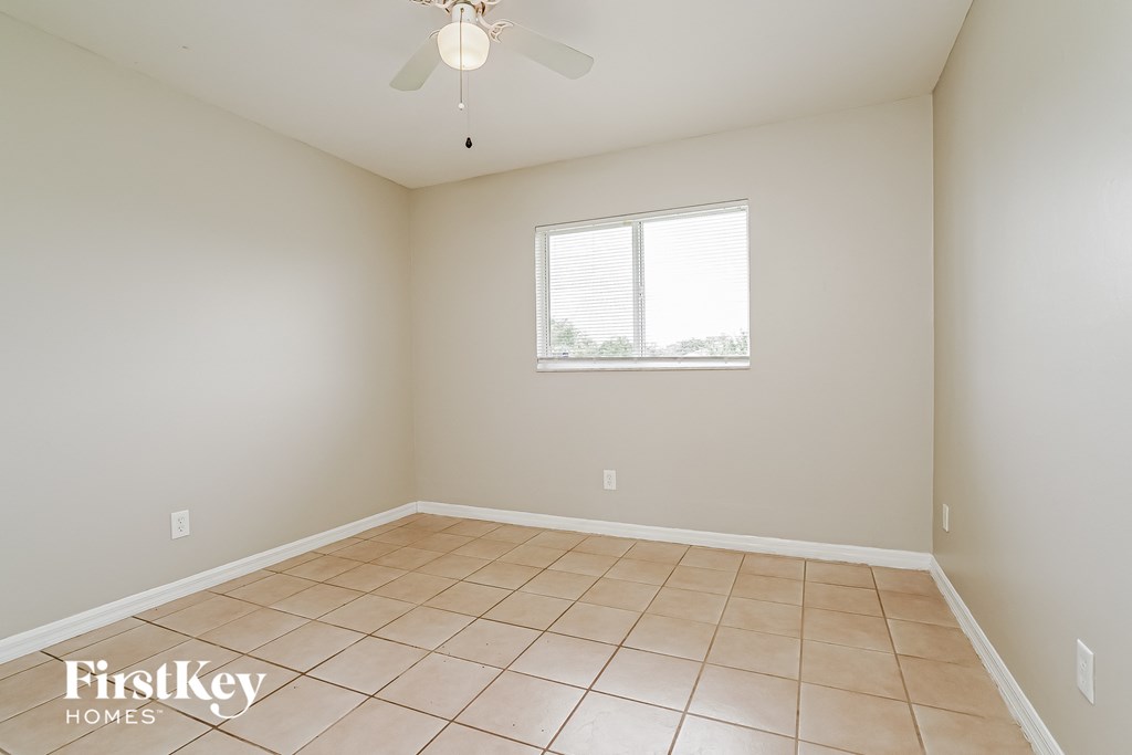an empty living room with a ceiling fan and a window