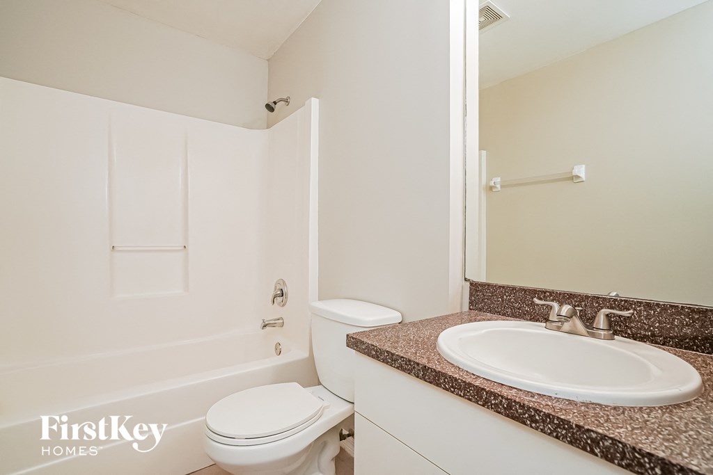 a white bathroom with a sink and toilet and a mirror