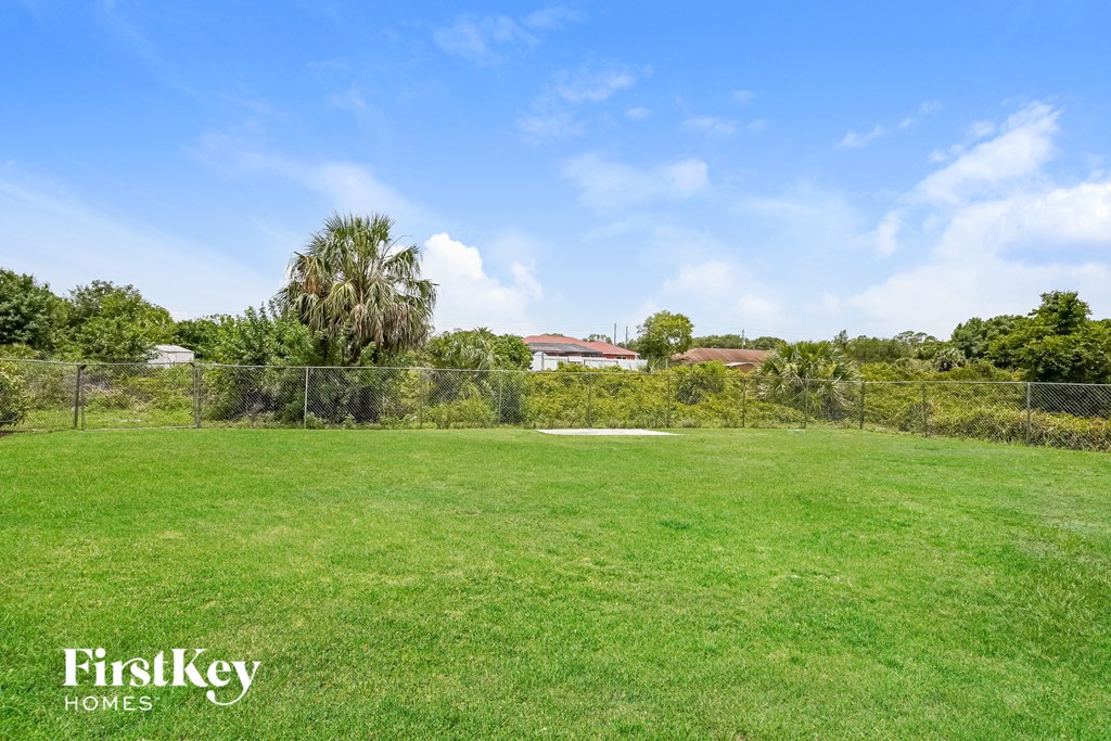 a large grassy field with a chain link fence