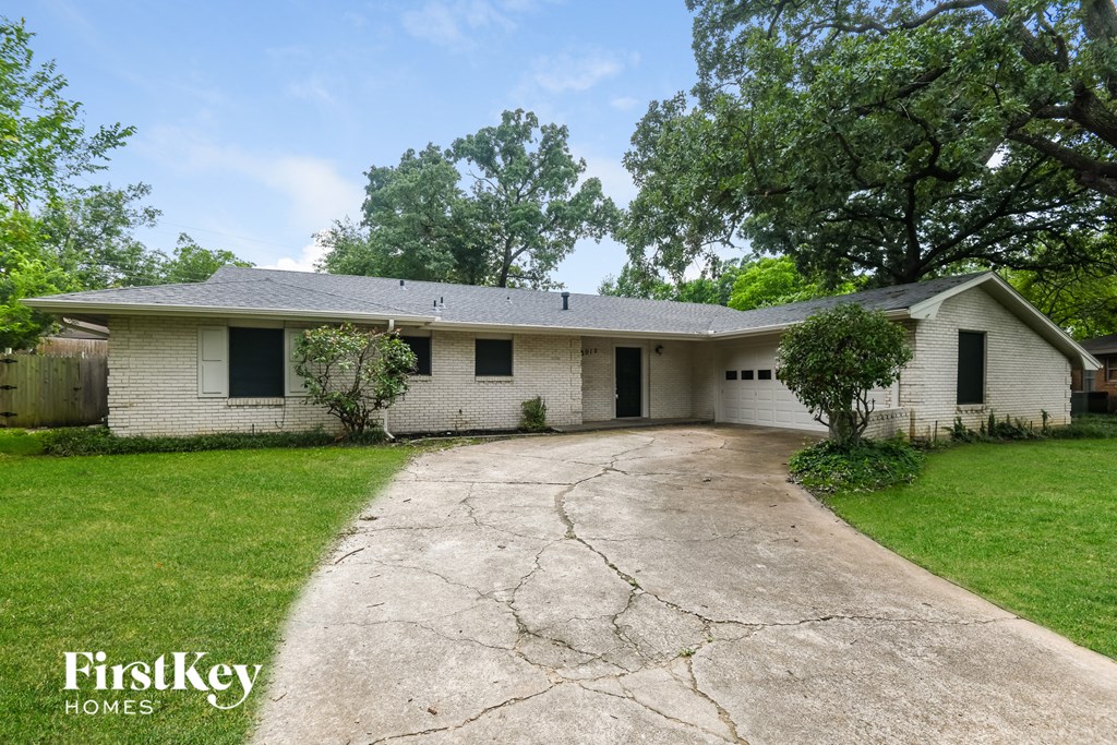 a white house with a cracked driveway in front of it