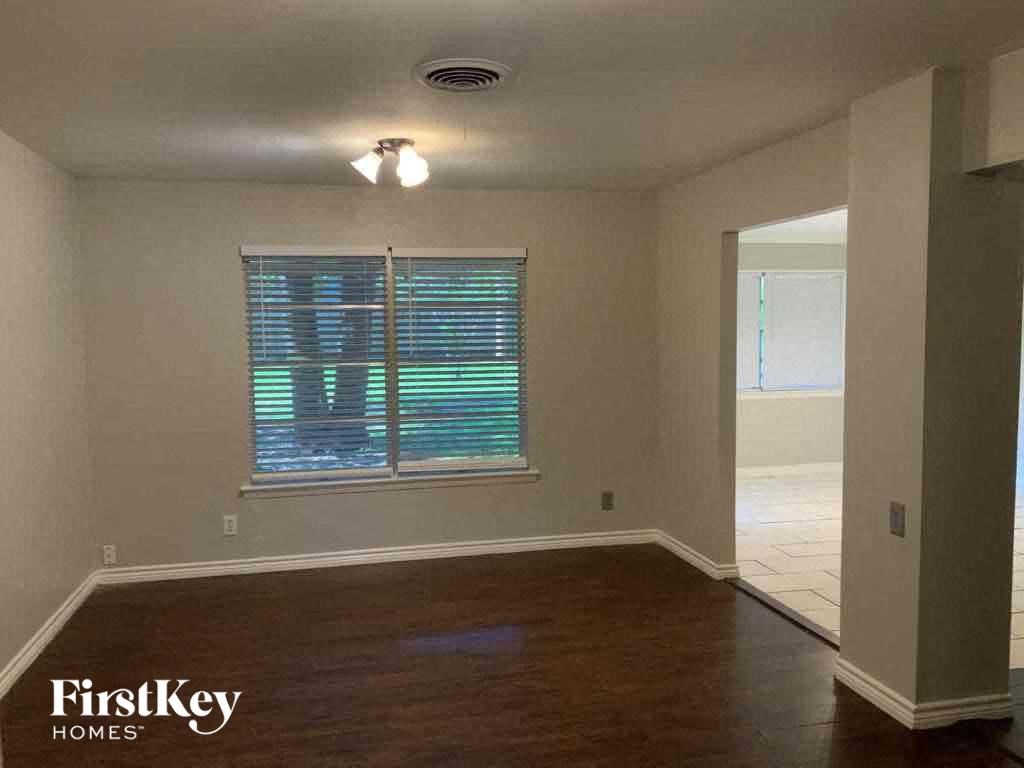 an empty living room with a window and wooden floors