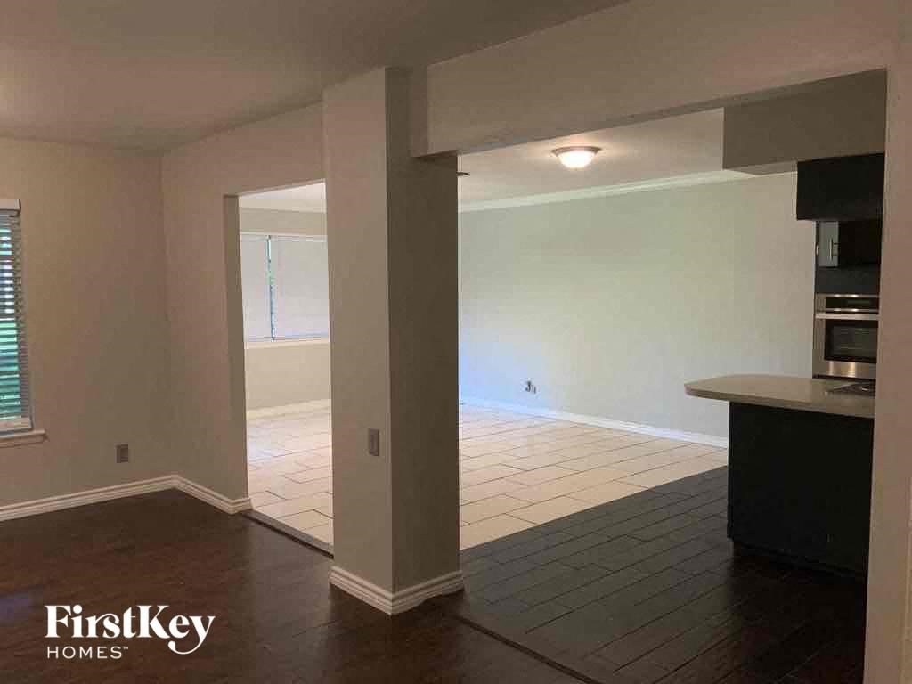 an empty living room with a kitchen and a dining room