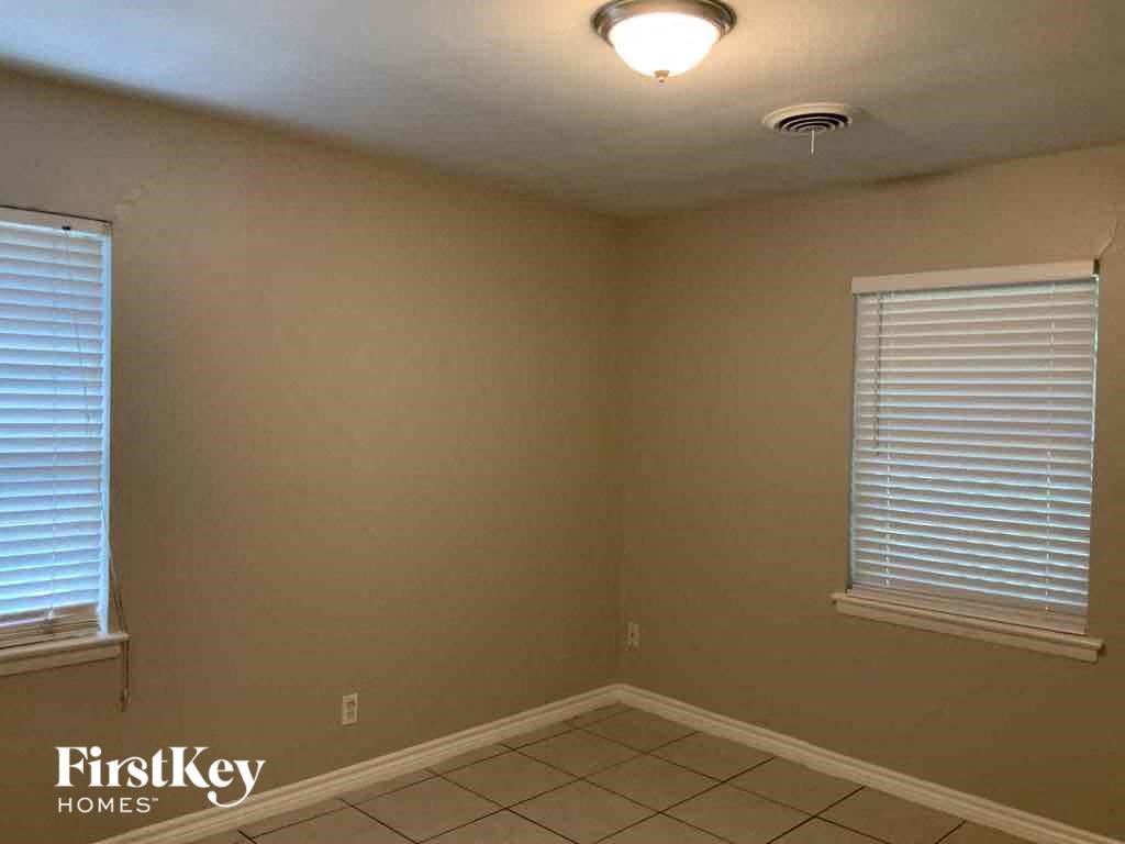 a corner of a room with two windows and a light on the ceiling