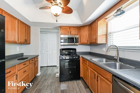 a kitchen with wooden cabinets and black appliances and a ceiling fan