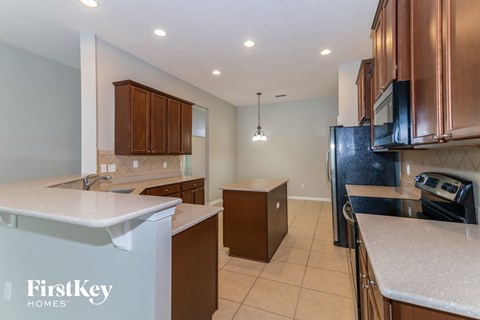 a kitchen with wood cabinets and white counter tops and a black refrigerator