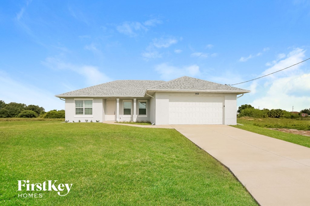 a small white house with a driveway and a lawn