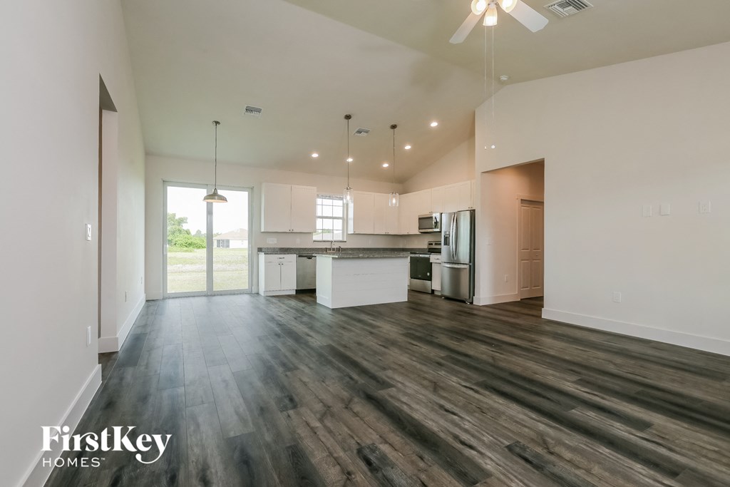 an empty living room and kitchen with wood flooring