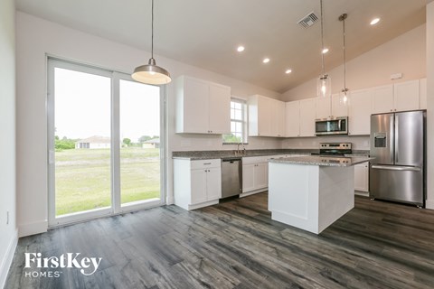 a kitchen with white cabinets and stainless steel appliances and a large window