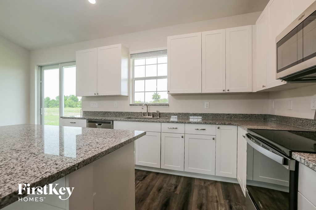 a white kitchen with granite counter tops and white cabinets